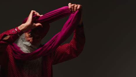 Low-Key-Studio-Lighting-Shot-Of-Senior-Sikh-Man-With-Beard-Tying-Fabric-For-Turban-Against-Dark-Background-Looking-In-Mirror-1